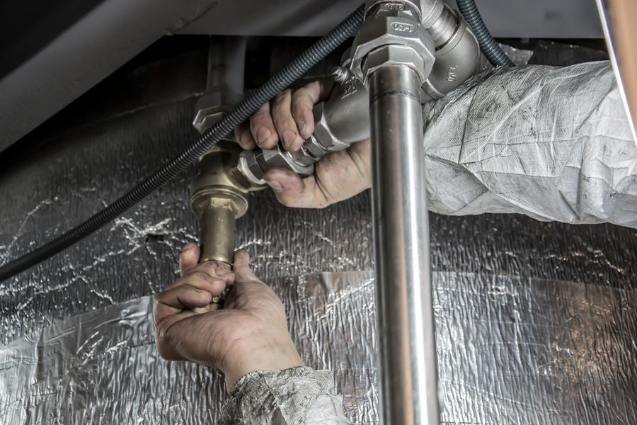 A plumber repairing copper supply lines under a sink
