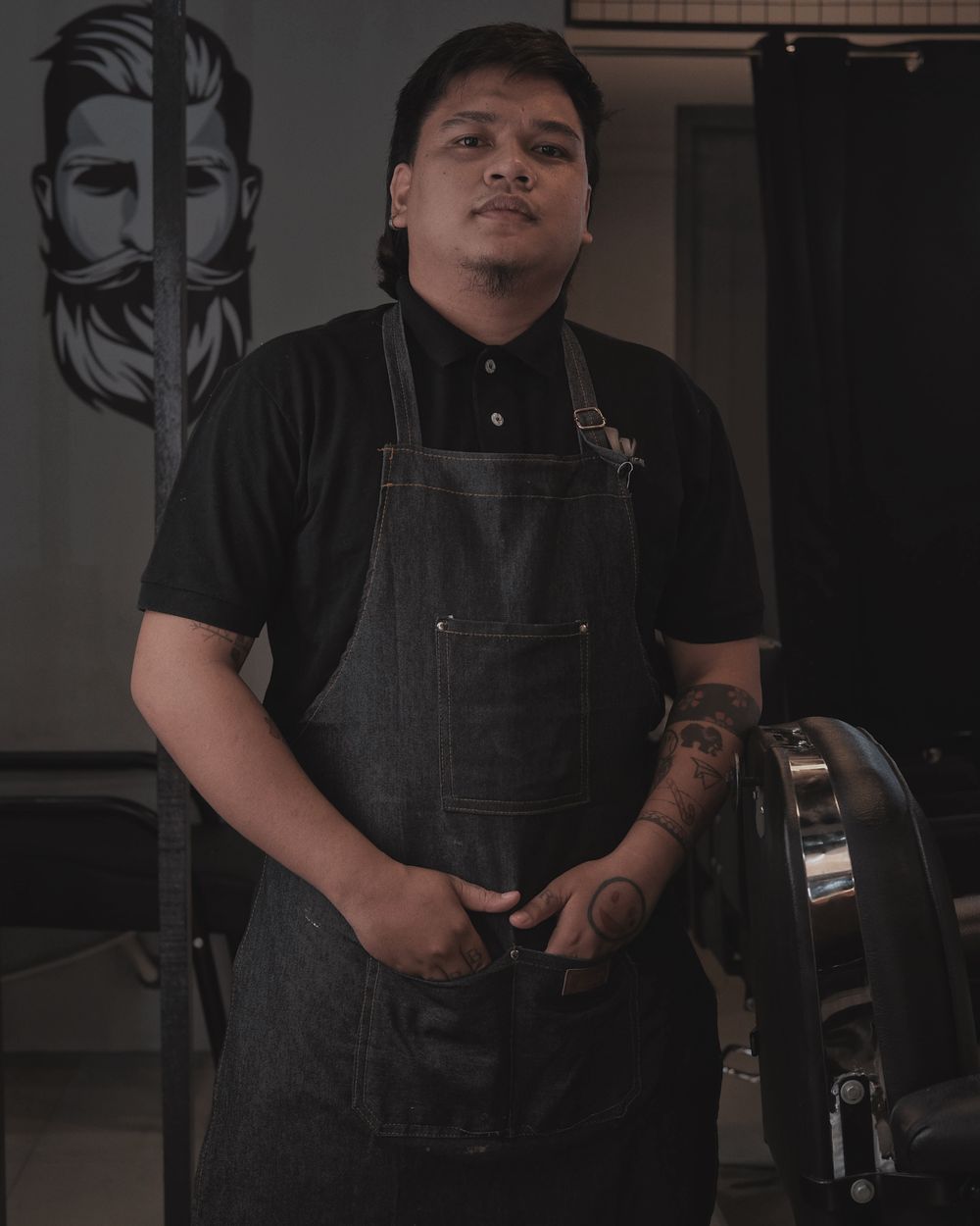 Portrait of Marcus, a tattooed barber in his apron