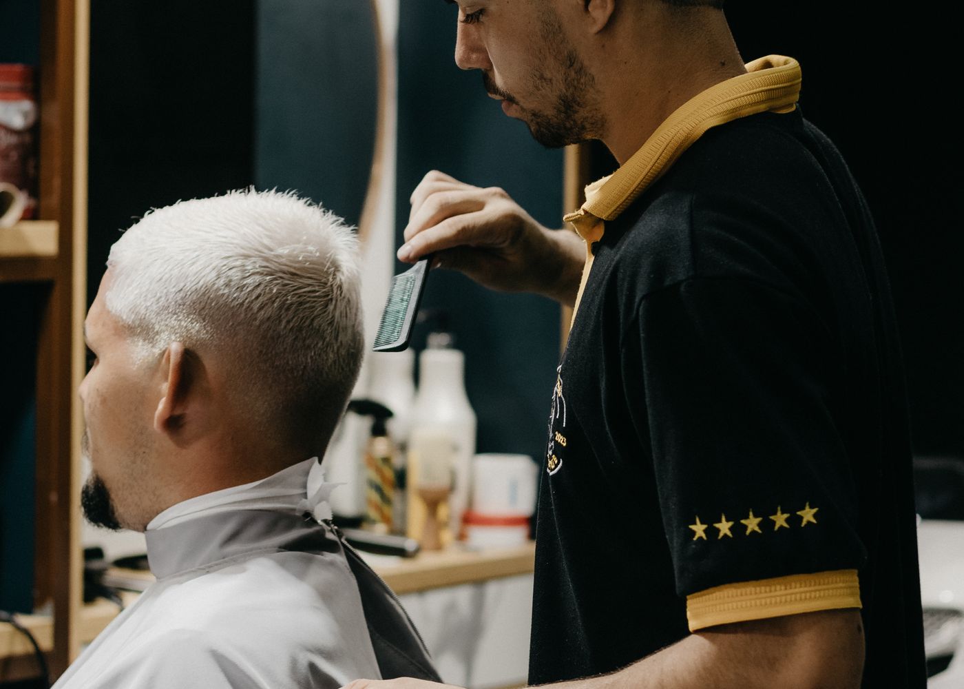 A barber mid-cut, blending a fade with clippers