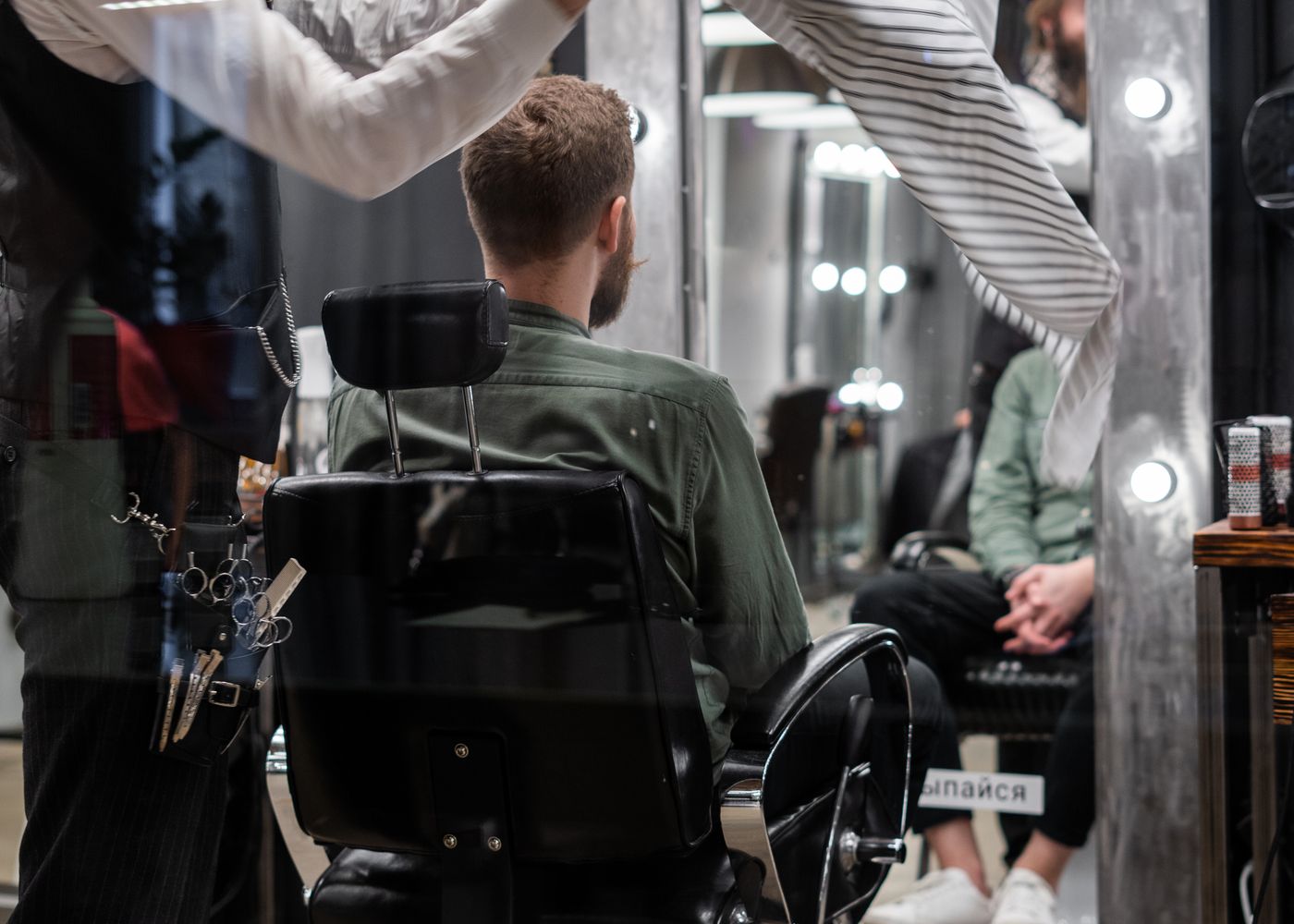 A barber leaning in to talk through a cut with a seated client