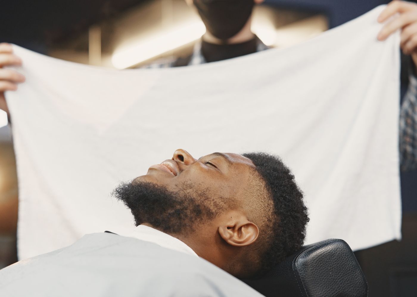 A hot towel being laid over a client at the end of a service