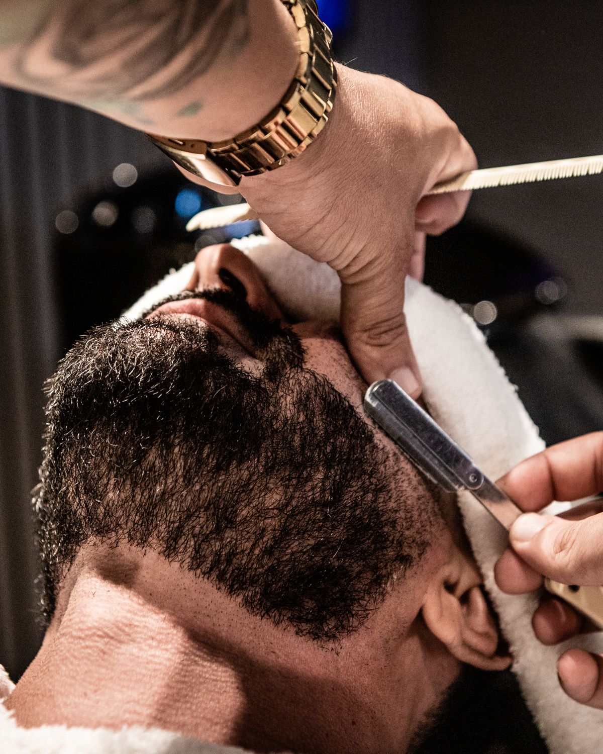 A barber shaping a client’s beard