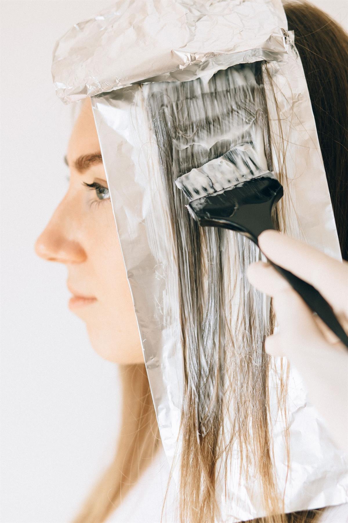 A colorist painting lightener onto sectioned hair in foils