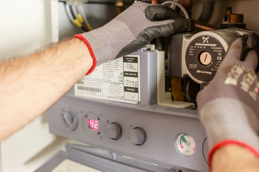 Gloved hands servicing a residential furnace and boiler unit