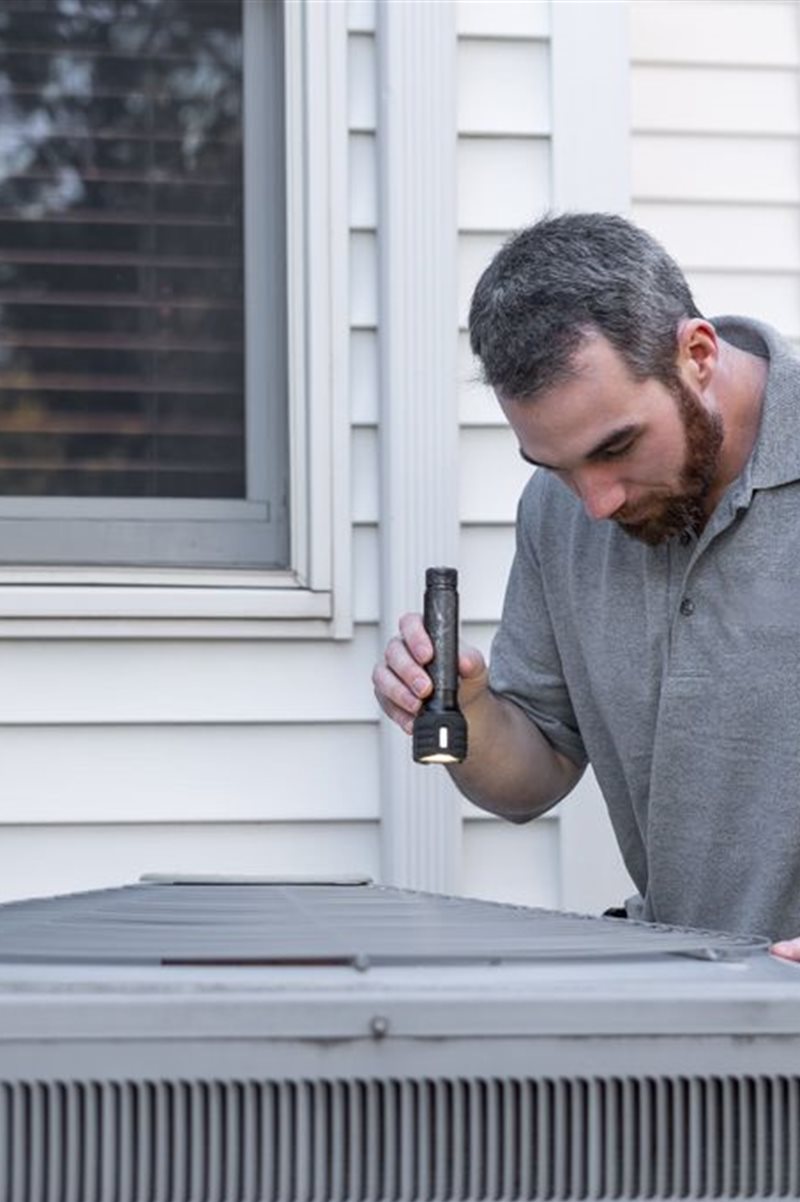 A Wasatch Air technician inspecting a home air conditioning unit